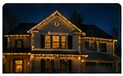 Night house photo with classic warm-white roofline lighting in the first Design It Your Way card.
