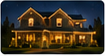 Thumbnail photo of last year's holiday lighting design on a two-story home at night with warm roofline and tree lights.